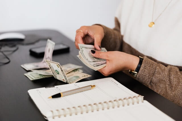 Início crop payroll clerk counting money while sitting at table